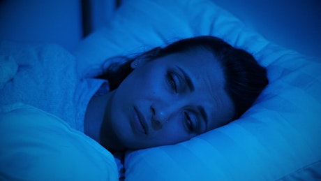 Woman in her bed unable to sleep due to the noise.