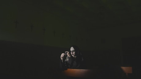 Woman in nun costume on Halloween praying in church