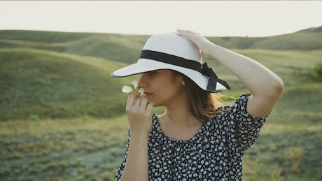 Woman in the countryside smelling a white flower