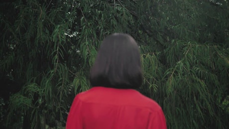 Woman in the foreground with her back facing some trees.