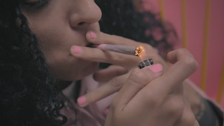 Woman lighting a marijuana cigarette.