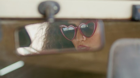 Woman looking in rear view mirror.