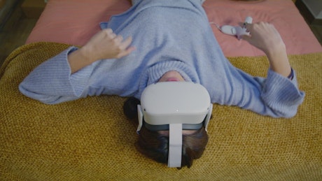 Woman lying down wearing virtual reality goggles.