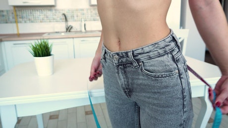 Woman measures waist to track weight loss.