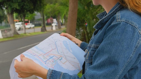 Woman on the street locating herself with a map of the city
