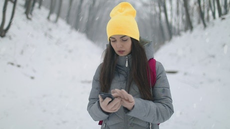 Woman on winter hike uses app on mobile phone.