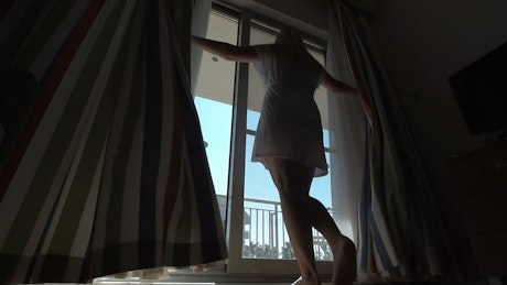 Woman opening the curtains.