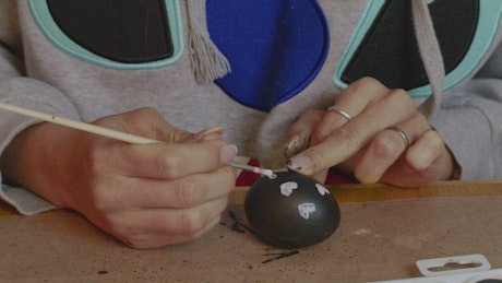 Woman painting hearts on an egg.