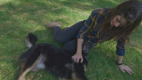 Woman petting her dog on the grass