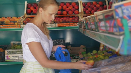 Woman picking fruit in a small shop.
