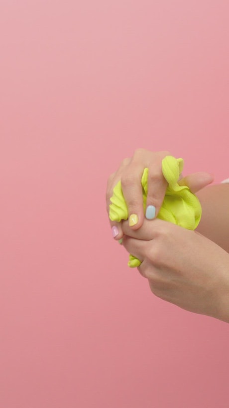Woman playing with green plasticine, stretching and squeezing it.