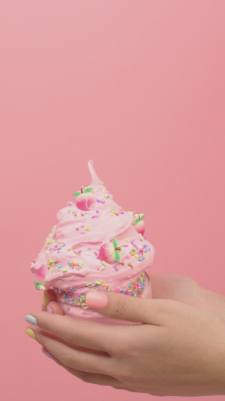 Woman playing with pink plasticine in the shape of ice cream.