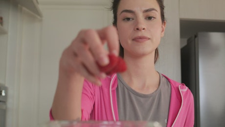 Woman preparing a smoothie with fruit and milk.