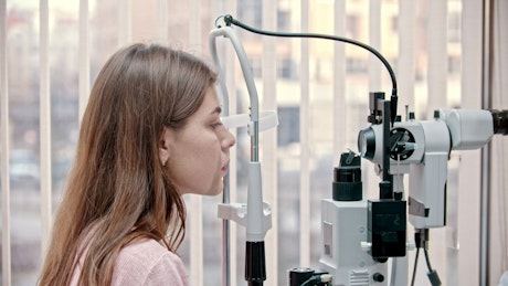Woman putting chin on a modern vision test device.