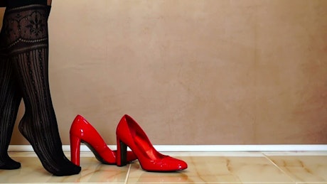 Woman putting on red high heels.