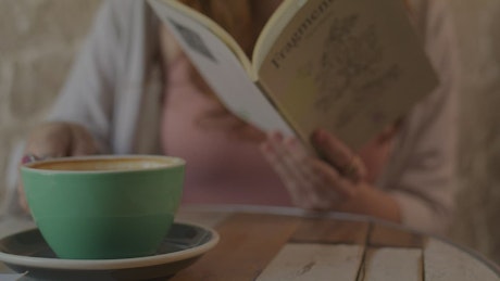 Woman reading a book while she drinks coffee