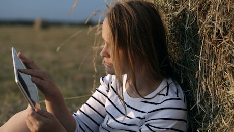 Woman resting in a field with her tablet.