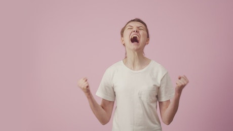 Woman screaming with rage against a pink background.