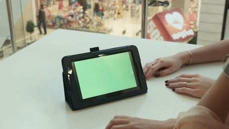 Woman scrolling on a tablet in a shopping mall.