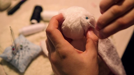 Woman sewing a toy plush doll.
