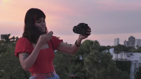 Woman shooting a blog with city background at the sunset.