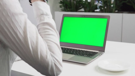 一位女士在笔记本电脑的绿色屏幕前喝着咖啡