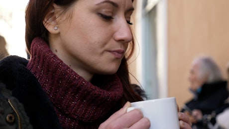 Woman sips on a cup of coffee before looking at the camera.