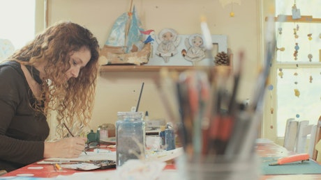 Woman sitting in a studio painting with watercolors.