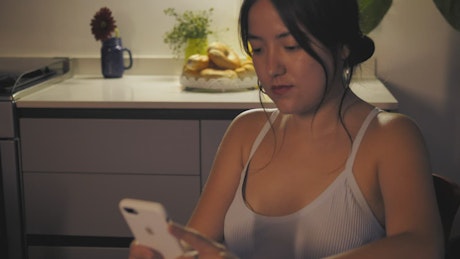 Woman sitting in the kitchen while texting