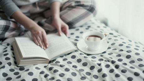 Woman sitting on a polkadot quilt reading a book.