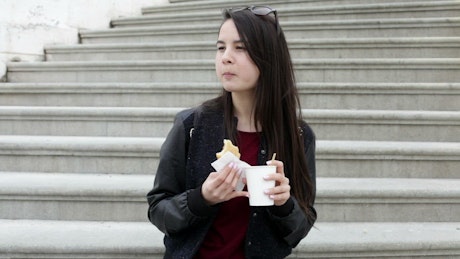 Woman sitting on steps eating a sandwich.