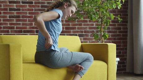 Woman sitting on the couch with lower back pain.