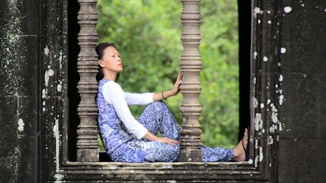 Woman sitting over a window in a Buddhist temple.