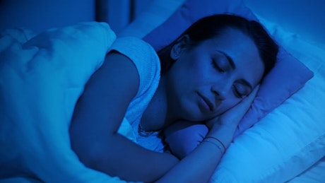 在昏暗的蓝光中睡在床上的女人