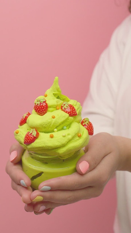 Woman squeezing green plasticine into ice cream shape.