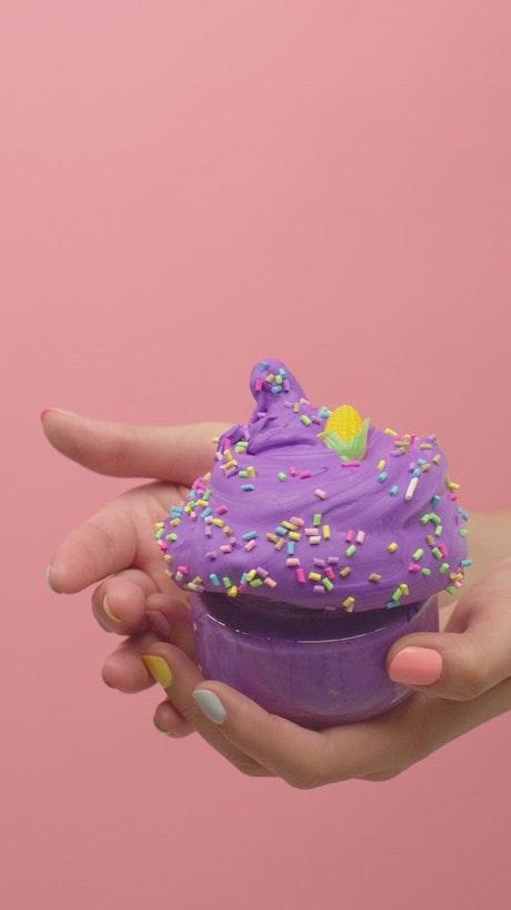 Woman squeezing purple plasticine into ice cream shape.