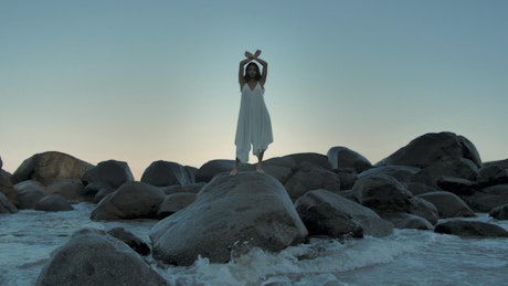 Woman standing on big rocks near the water
