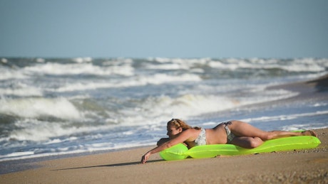 Woman sunbathing on the seashore on a floaty.