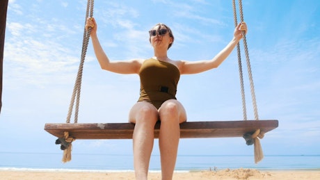 Woman swinging on a sunny beach.