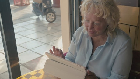 Woman using a tablet from a city cafe.