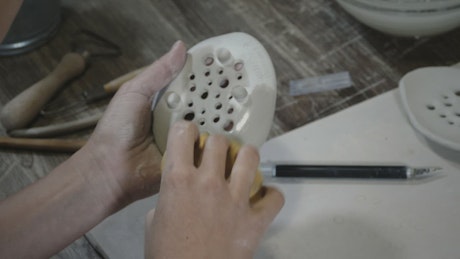 Woman using a wet sponge on a clay object