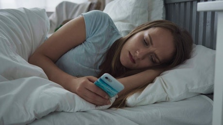 Woman using her phone in bed.