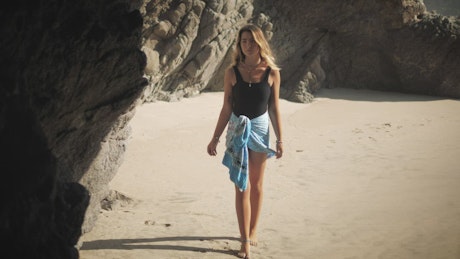 Woman walks into cave on the beach.