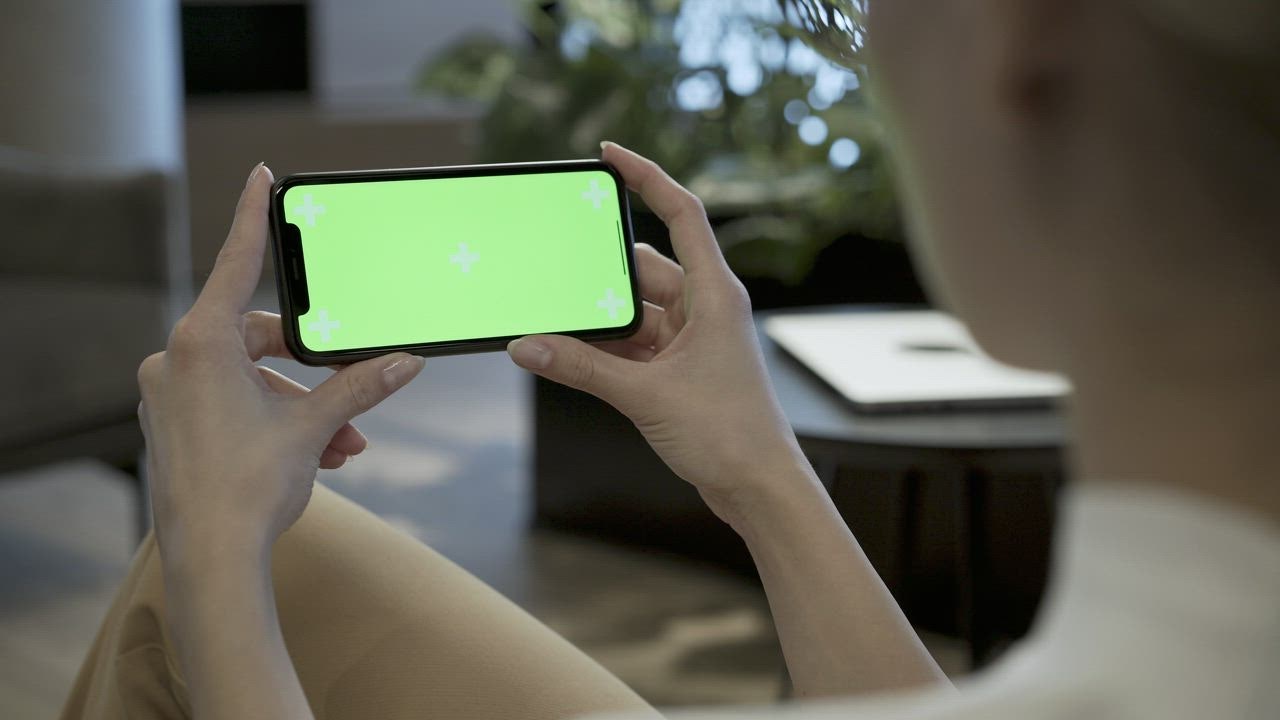 Woman watching a mobile phone with a green screen - Free Stock Video