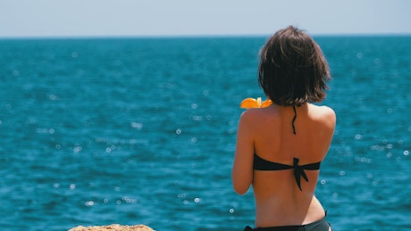 Woman wearing bikini and drinking on the beach.