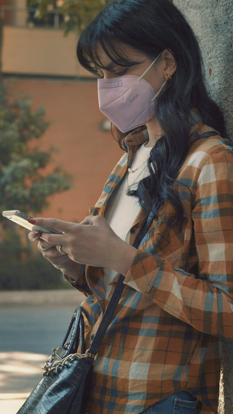 Woman with a face mask texting on the phone.