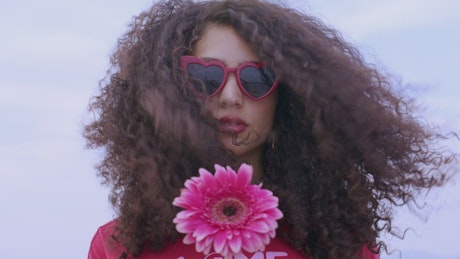 Woman with a pink rose and sunglasses.
