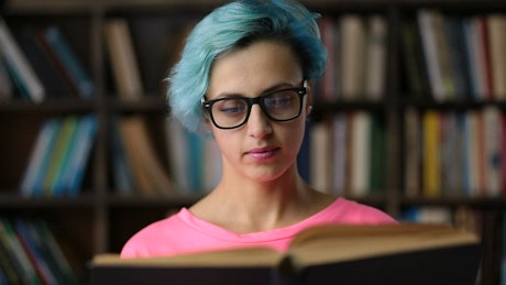 Woman with glasses reading a book.