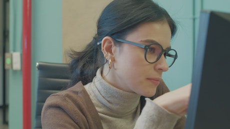 Woman with glasses working in the office.