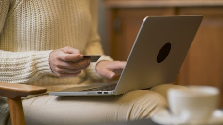 Woman with laptop holding a credit card.